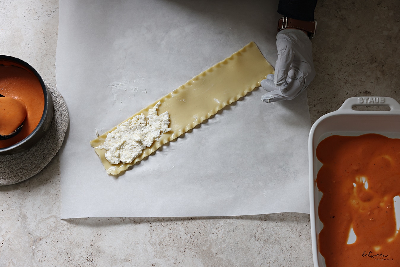 Cheese mixture on a strip of lasagna, on a piece of parchment paper.