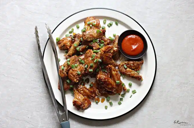 Wings, plated - topped with scallions - and hot sauce