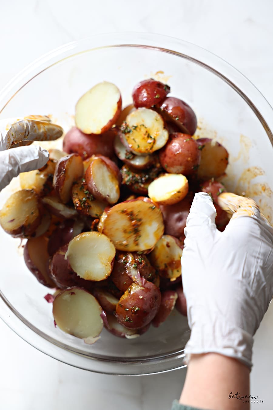 Coating the sliced potatoes in the mixture - with gloved hands.