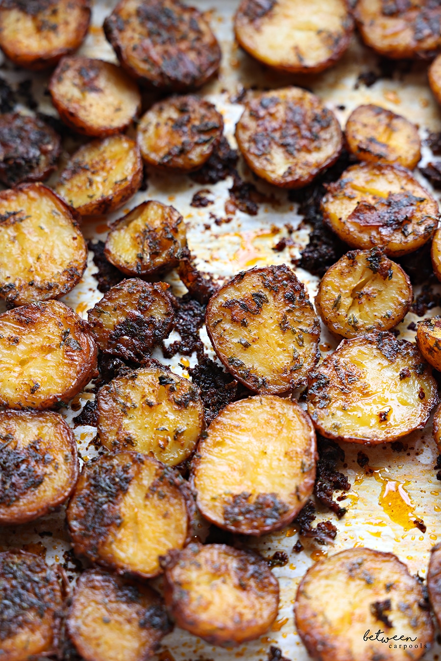 Baked red potatoes on a parchment lined baking sheet.