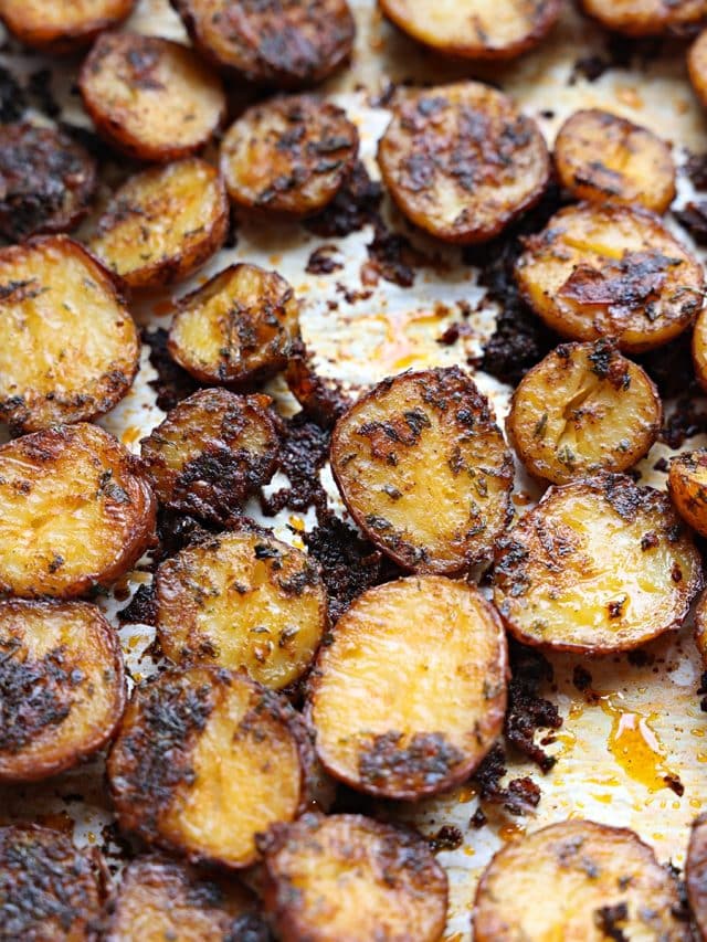 Baked red potatoes on a parchment lined baking sheet.