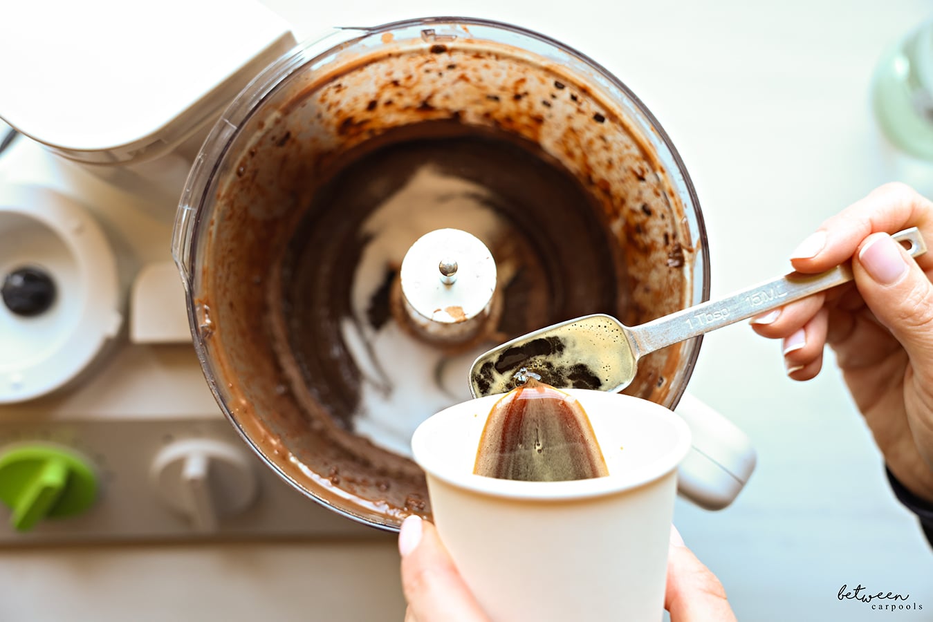 Adding coffee and sugar to puréed chocolate in the bowl of a food processor fitted with the “S” blade.