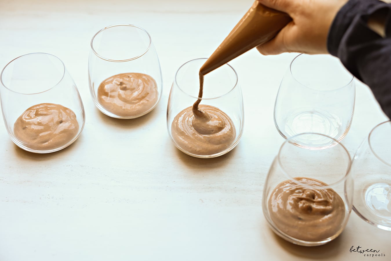 Piping mousse into glass cups.