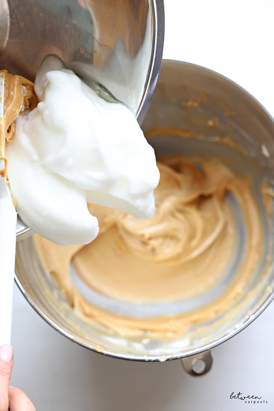 Adding beaten egg whites to the bowl with the peanut butter layer.