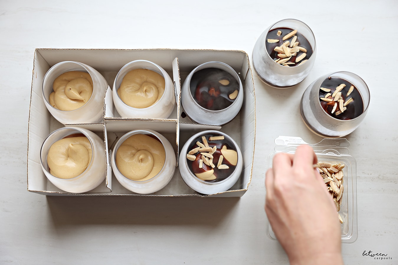 Topping each mousse cup with slivered almonds.