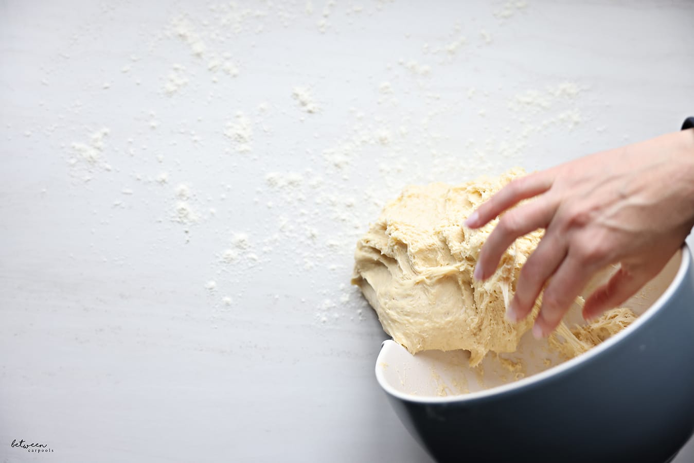Removing the dough from the bowl onto the counter sprinkled with flour.