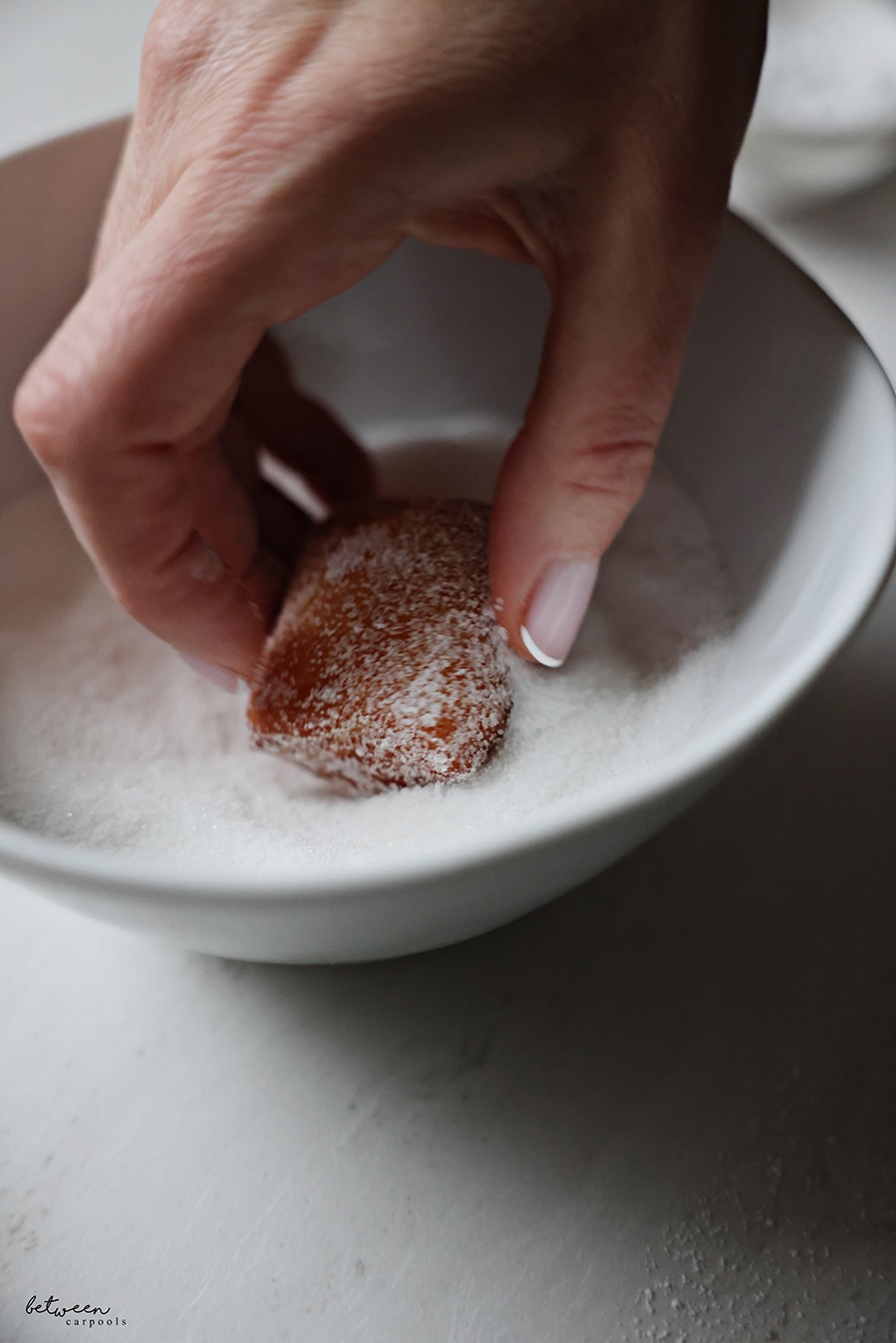 Tossing a beignet in sugar.
