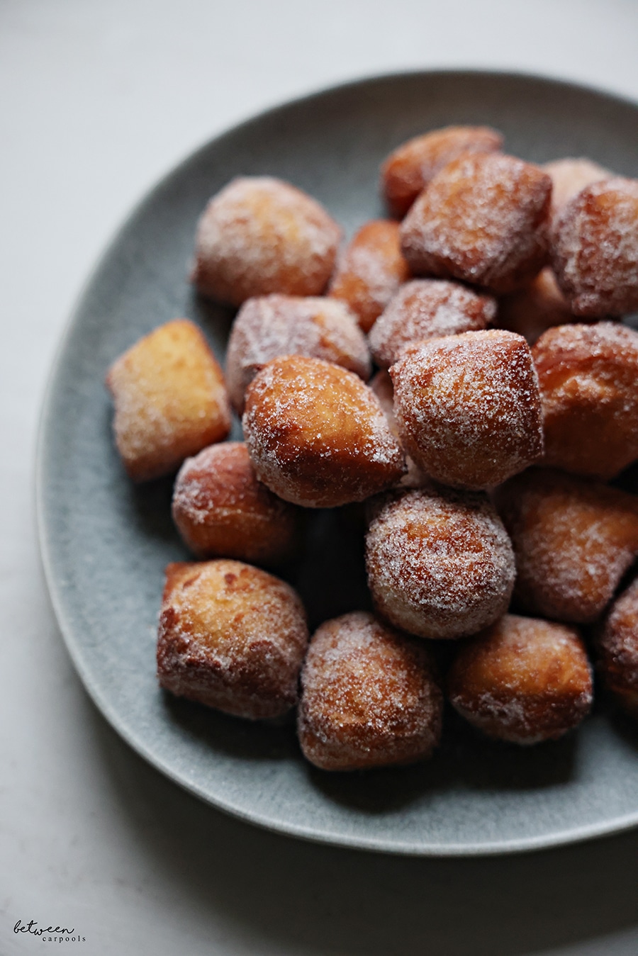 Closeup of a plate of beignets tossed in sugar.