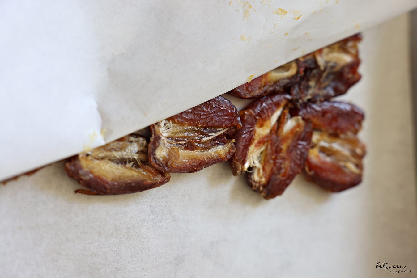 Closeup of flattened layer of dates on parchment paper.