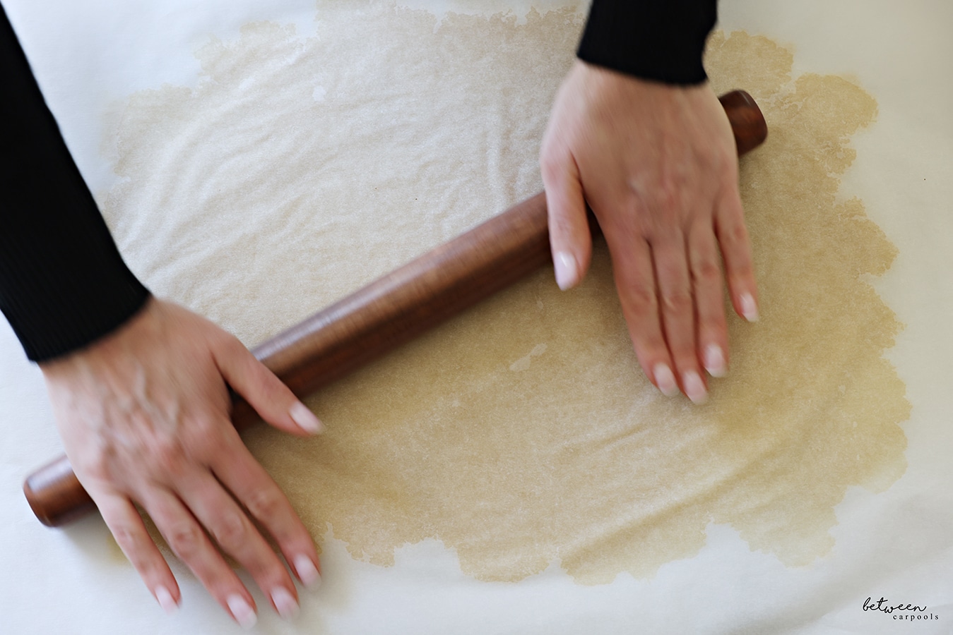 Rolling one half of dough on a piece of parchment paper, covered with another piece of parchment.