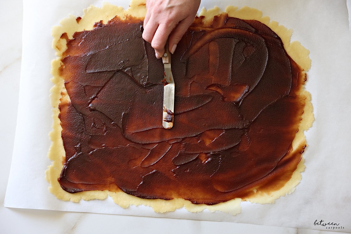 Smearing date spread on one half of dough rolled flat into a large rectangle.
