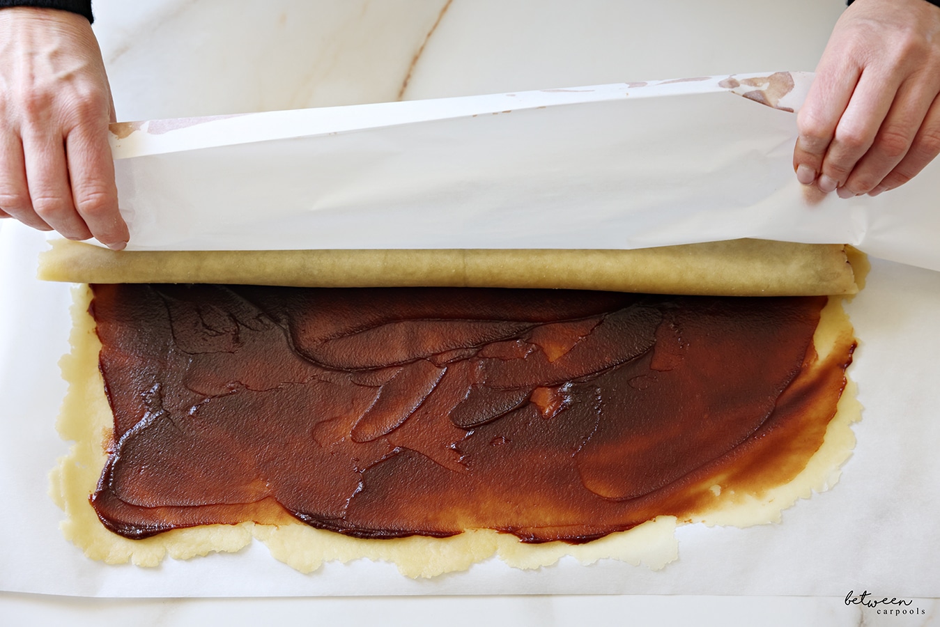 Rolling the dough rolled flat into a large rectangle jelly-roll style.