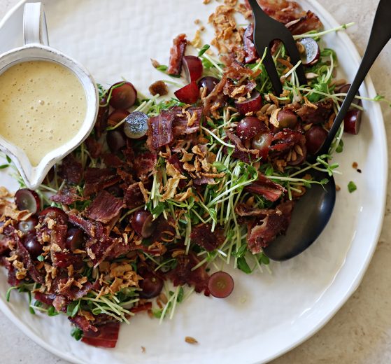 Pea Shoot Salad, plated, with a creamer of salad dressing.