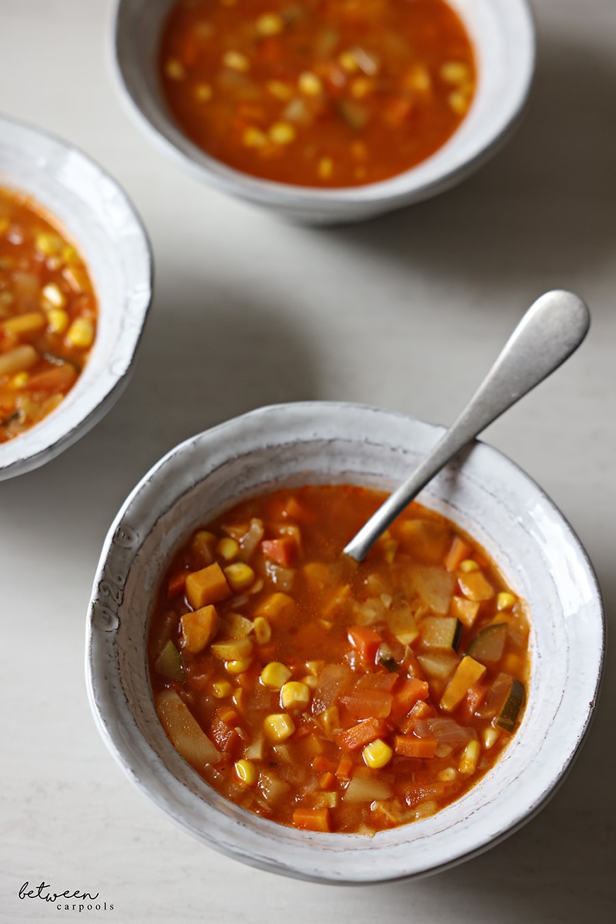Three bowls of Diced Veggie Soup, one with a spoon.
