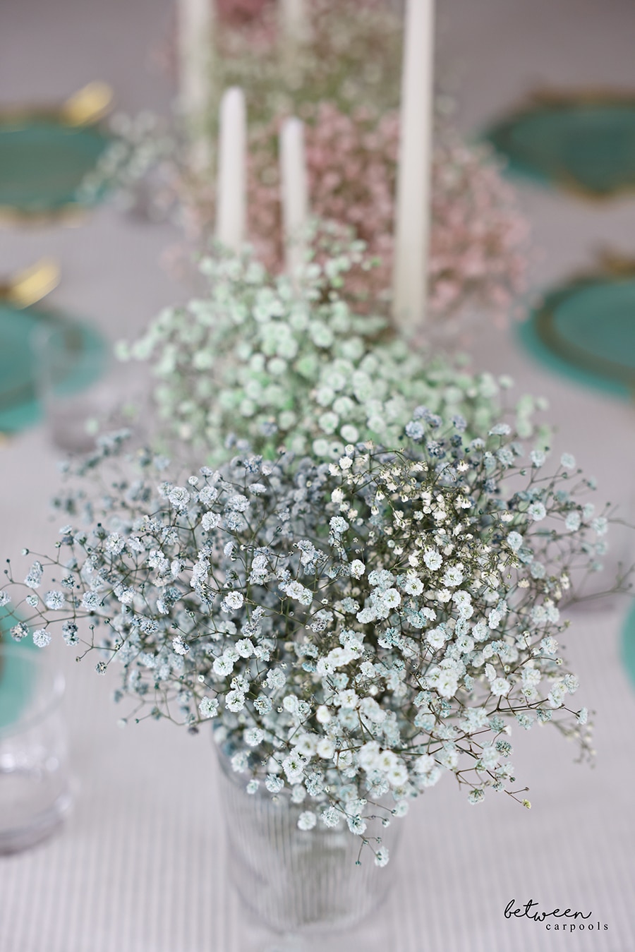 Closeup of colored baby's breath in vases on a set table.