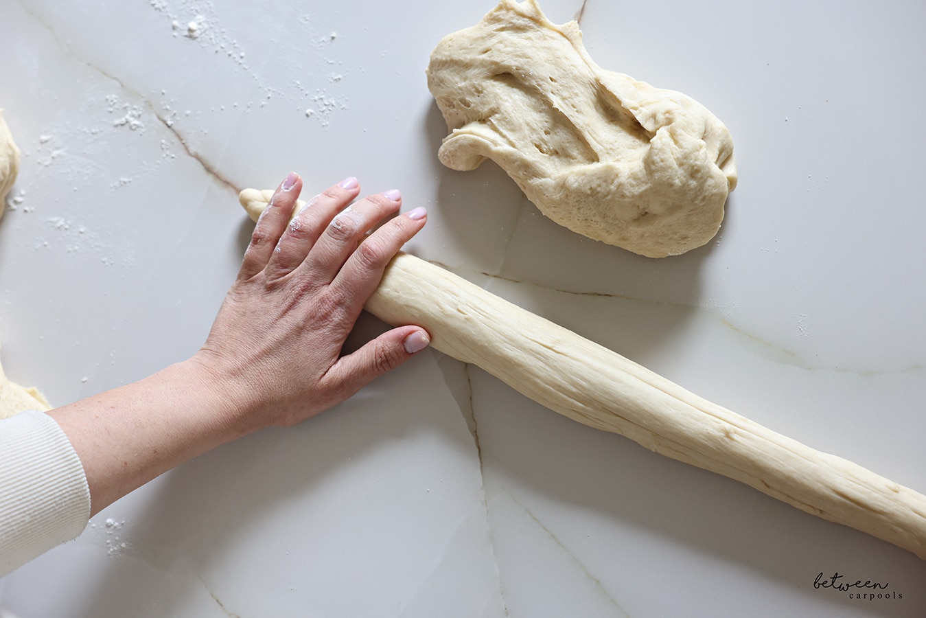 Rolling one piece (each half) of challah dough into a long strand.