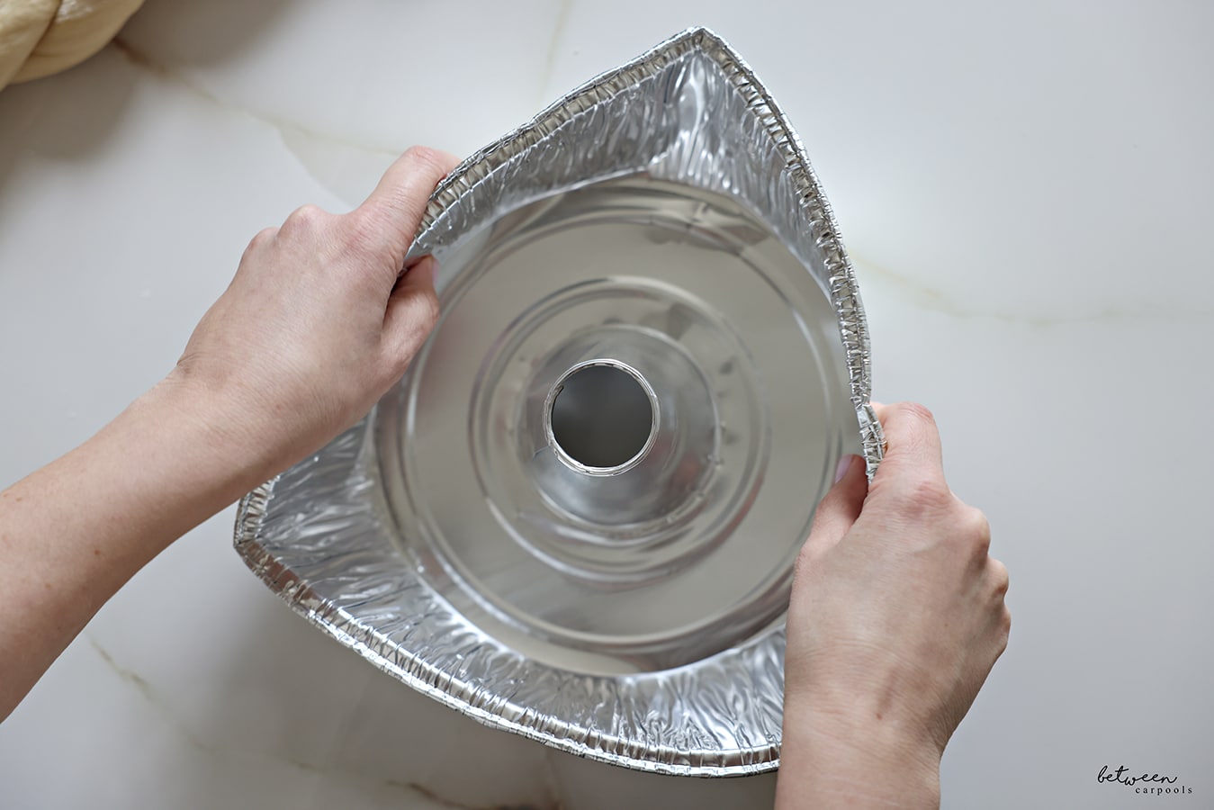 Bending in the sides of a 10" aluminum foil tube pan so that you have a triangle.