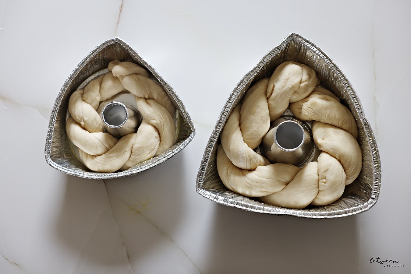 Challah twists - made by twisting two longs strands of challah dough - wrapped around the tube of an 8" and 10" aluminum foil tube pan with its sides bent in to resemble triangles.