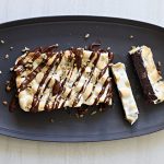 Rocky Road Marshmallow Brownie loaf on a platter with Almond Butter Ganache topping and walnut nibs.