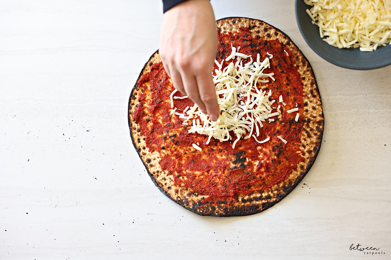 Topping one round Shmurah Matzah with a thin layer of seasoned tomato paste with cheese.