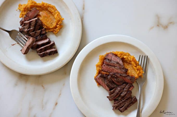 Grilled strip steak and mashed sweet potatoes, plated.