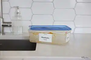 Dirty container labeled Meatballs near a kitchen sink.