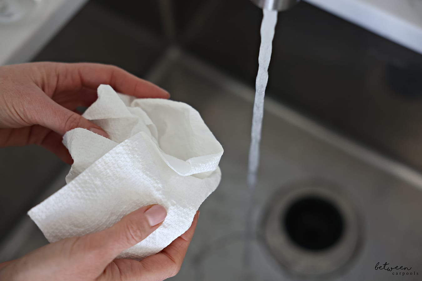 Holding a piece of paper towel near a running kitchen sink.