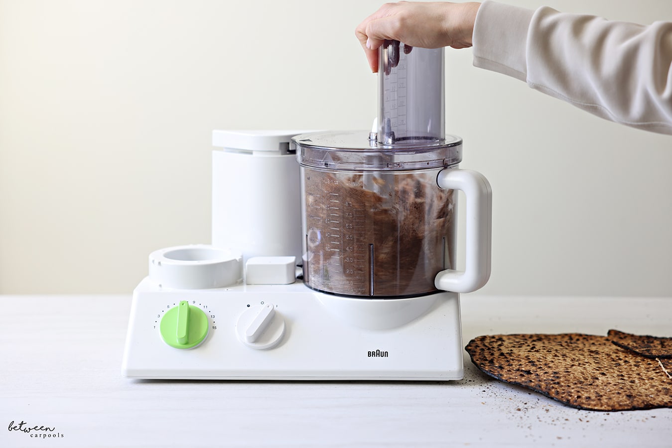 Pulsing round shemura matzah in Braun food processor. Some Matzah nearby.