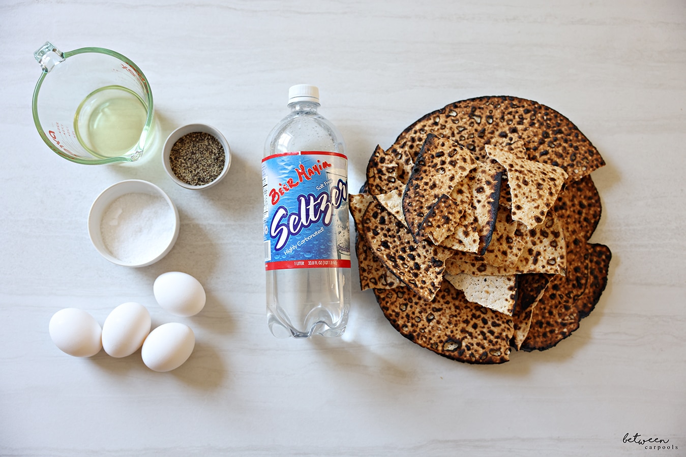 ¼ cup oil in a Pyrex glass measuring cup, salt and pepper, 4 eggs, Be'er Mayim Seltzer, round shemura matzah.