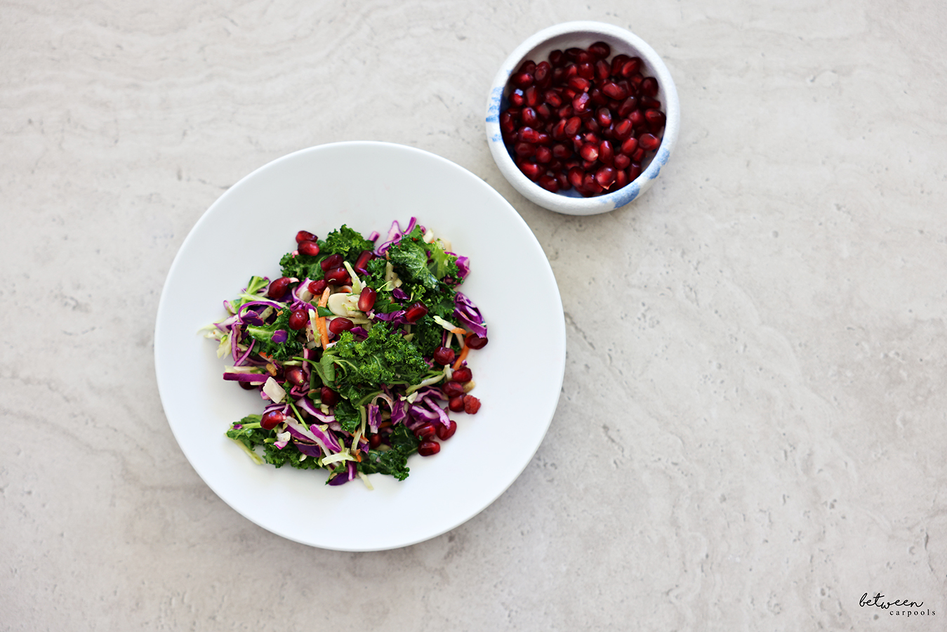 Crunchy Broccoli Slaw with Kale, plated, with pomegranate seeds. More pomegranate seeds on the side.