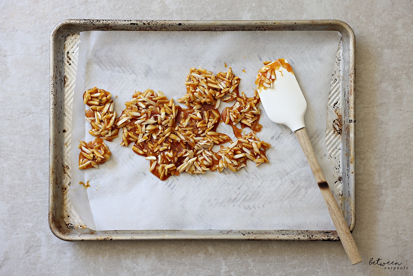 Praline on a parchment lined baking sheet with a spatula.