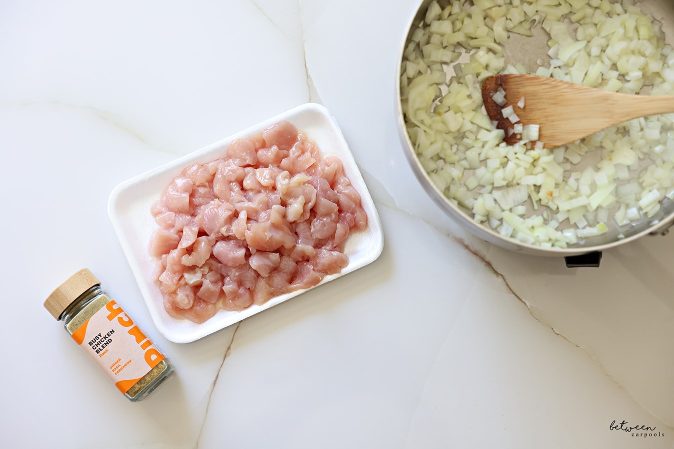 Pinch Busy Chicken Blend, a tray of “stir fry-sized” chicken cutlets, and 1 large Spanish onion sautéing in a sauté pan.