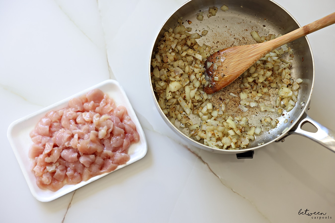 Sautéing a Spanish onion with Pinch Busy Chicken Blend in a sauté pan. A tray of “stir fry-sized” chicken cutlets nearby.