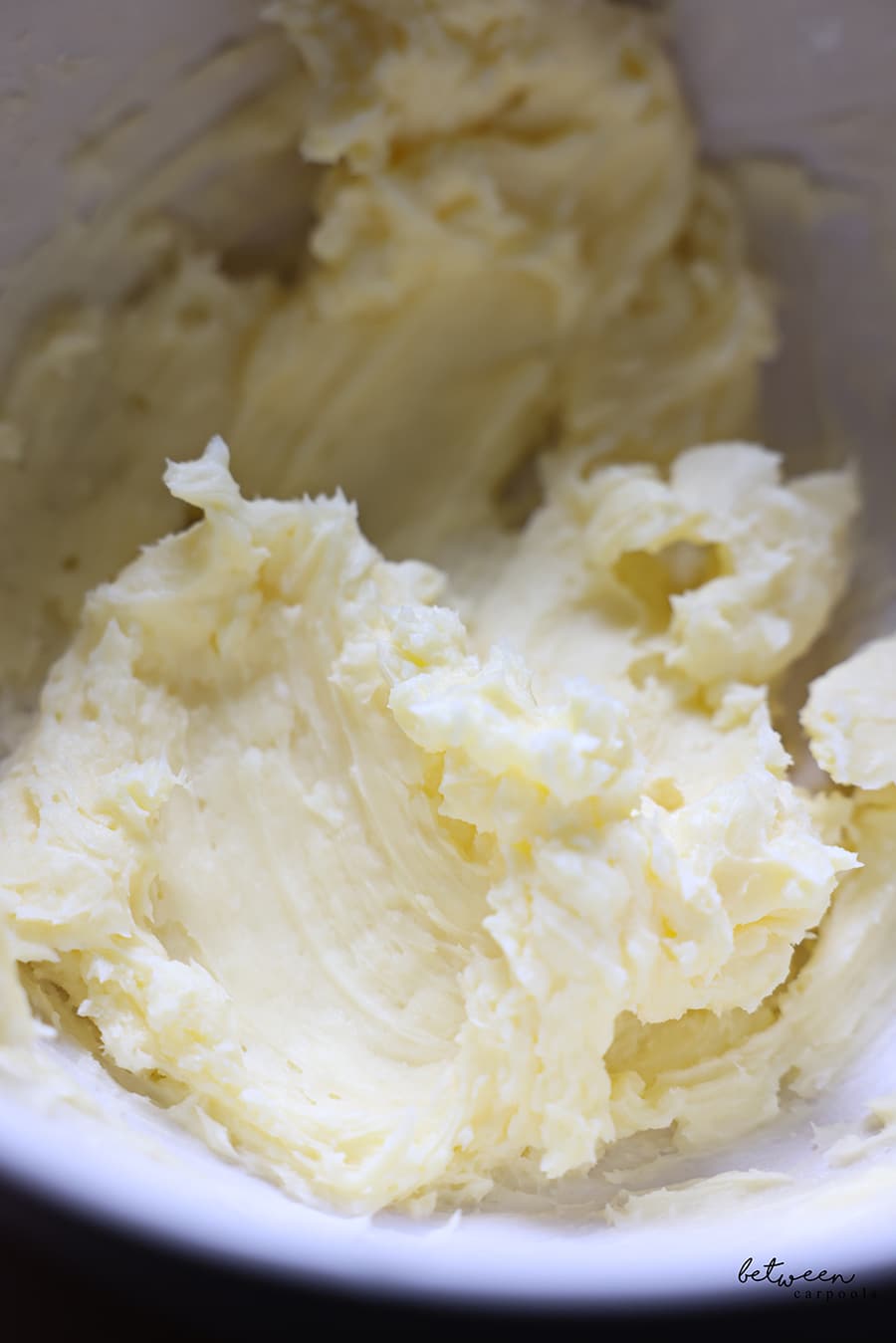Butter and sugar mixed into an even light yellow color, in a mixing bowl.
