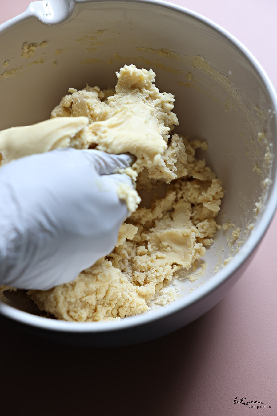 Mixing all ingredients, with a gloved hand, to form a French Butter Cookie dough.