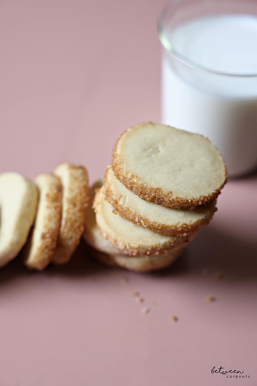 Stack of French Butter Cookies rolled in Turbinado sugar with a glass of milk behind.