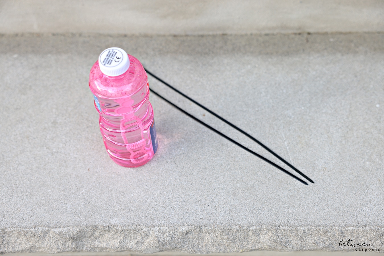 A Bubble Fun bottle and 2 12" zip ties on outdoor stairs.