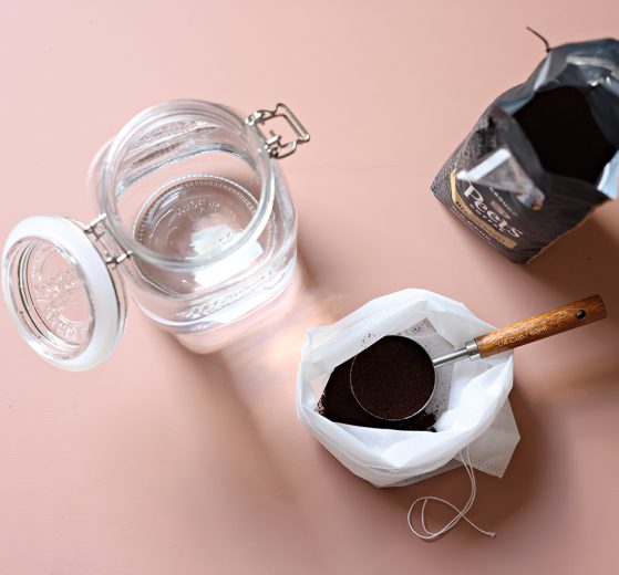 A wide-mouth glass jar, a cold brew bag with coffee grounds and a 1/4 cup measuring spoon, and an open bag of Peet's Big Bang Medium Roast Ground Coffee.