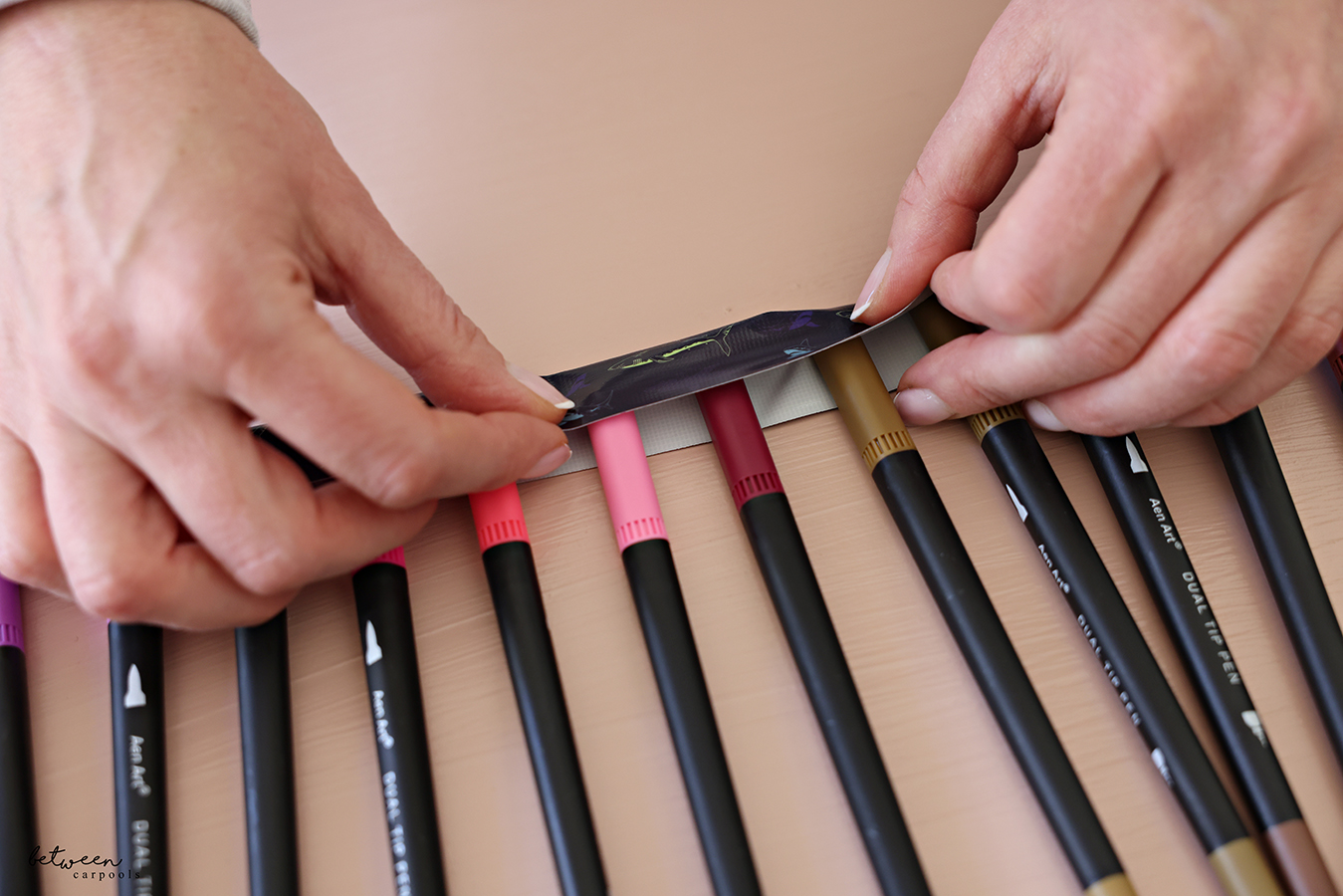 Folding the duct tape over the marker caps placed halfway on its sticky side.