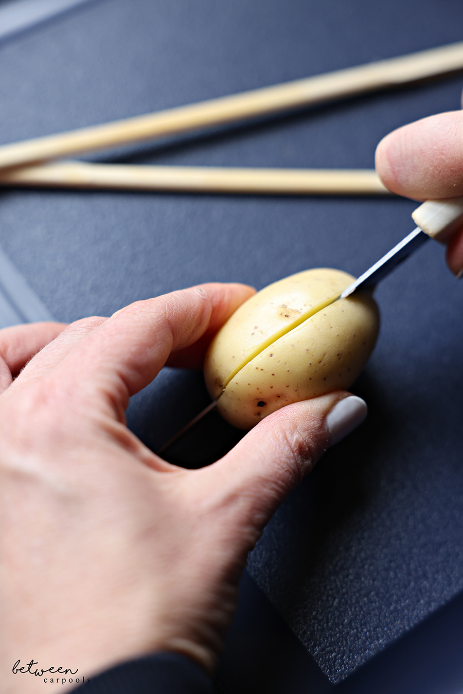 Slicing a baby golden potato in half lengthwise.