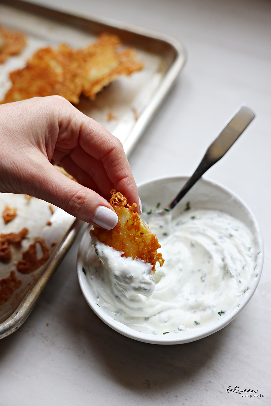 Dipping a crispy Parmesan potato half in ranch dip.