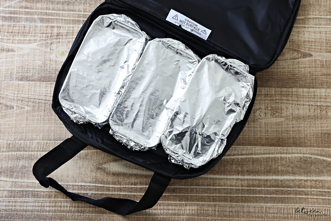 Three foil-covered disposable loaf pans with precooked food in a HOTLOGIC Max Large Portable Electric Food Heater. Open, Top View.