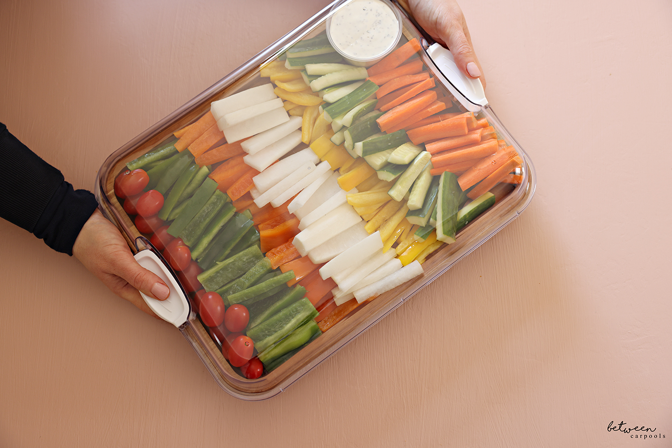 Holding a Fresh veggie platter on a bamboo tray with a Clear Locking Lid, White Handles.