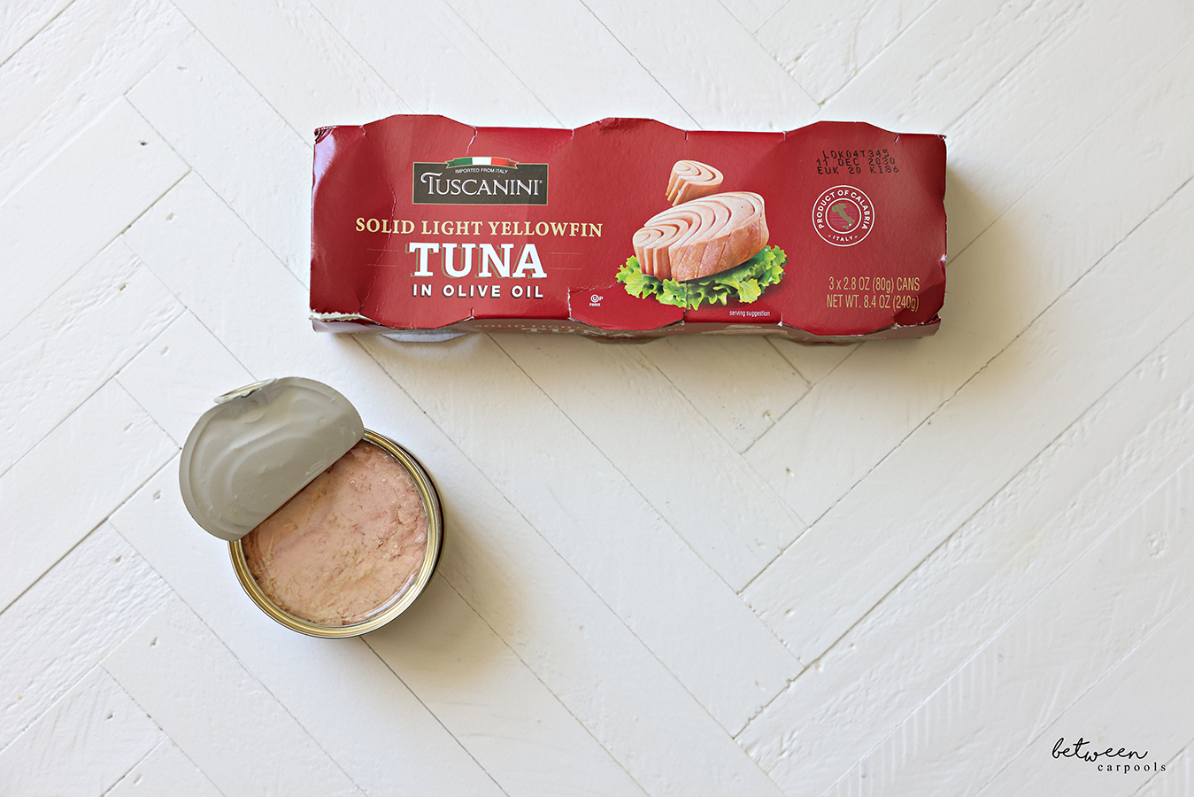 Top view of a package of Solid Light Yellowfin Tuna by Tuscanini plus one can almost fully open.