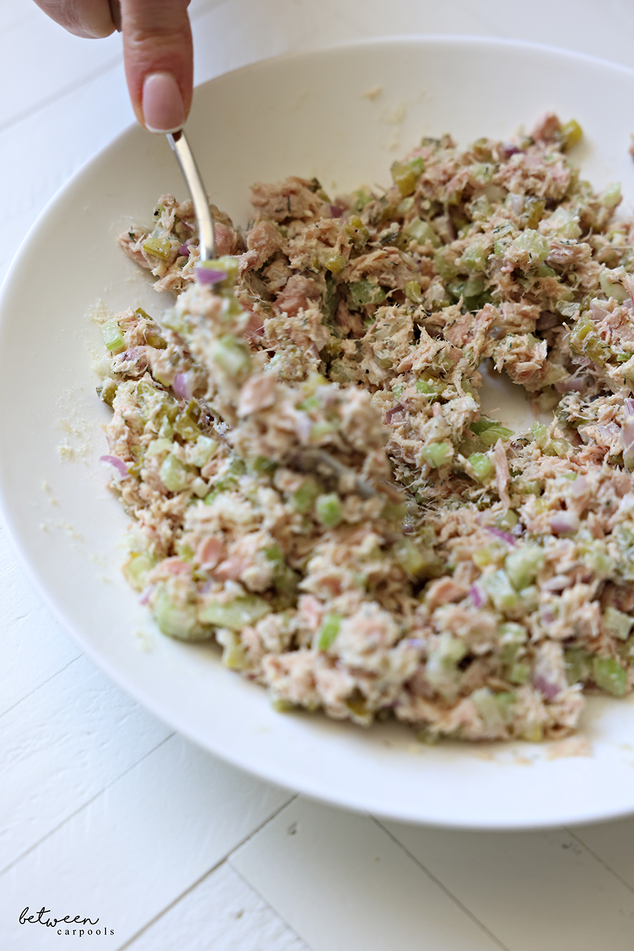 Mixing to combine tuna salad in a bowl.