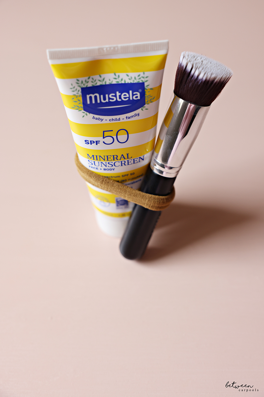 A Flat Top Kabuki Foundation Brush and a Mustela Mineral Sunscreen Lotion bundled with a hair tie.