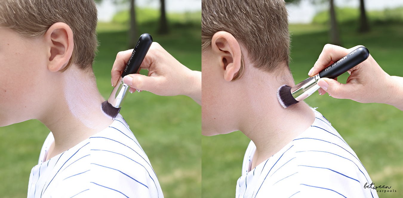 Applying sunscreen lotion with a Flat Top Kabuki Foundation Brush to a young boy's neck.