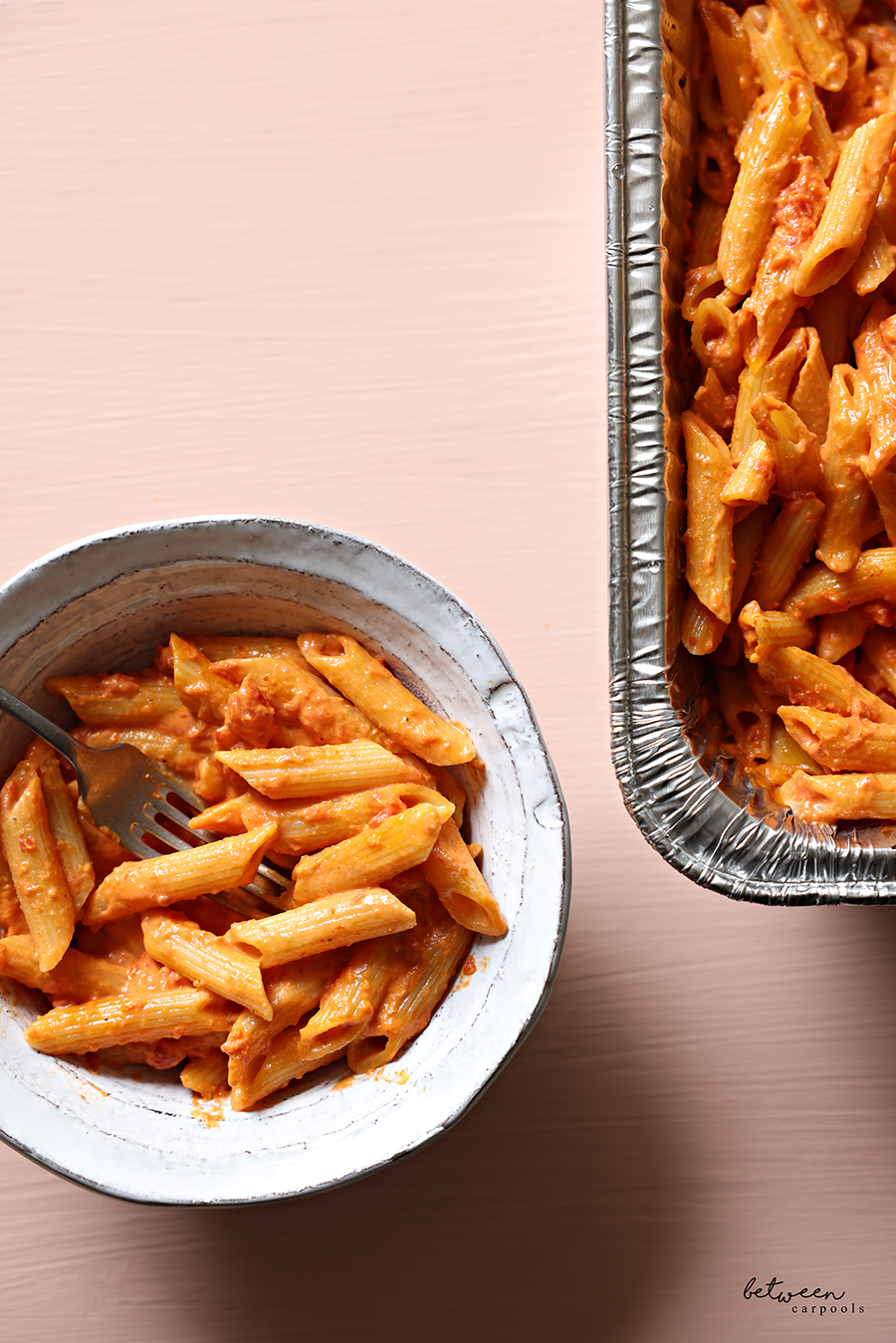Top view of a portion of 9x13 Penne Alla Vodka in a bowl and its aluminum foil pan.