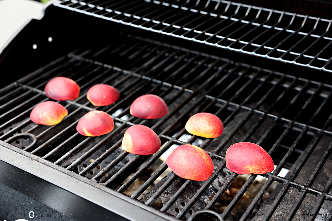 Halved and pitted peaches, cut side down, on the grill.