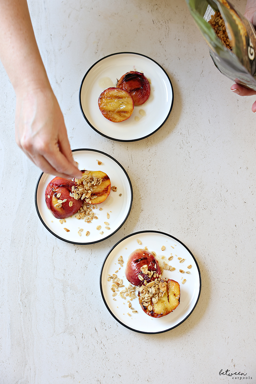 Adding granola to plated grilled peaches with bourbon glaze.